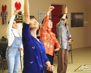 Four people standing with their right arms reaching up during a workshop for "Spring Moon."