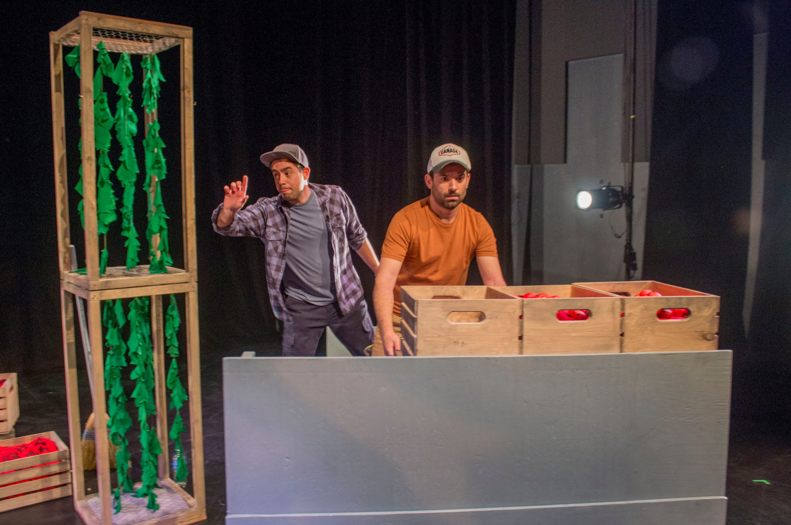 A production photo from "Harvest Justice: Twice the Speed of Lightning" showing two people working with crates of tomatoes.